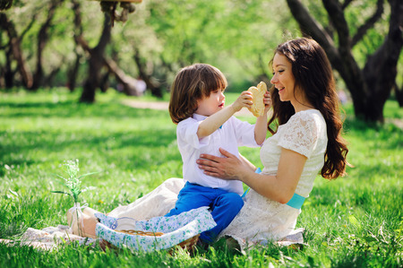 happy family on picnic for mothers day. Mom and toddler son eating sweets outdoor in spring or summer park. の写真素材