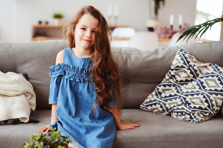 cute happy 5 years old child girl relaxing alone at home on cozy couchの写真素材