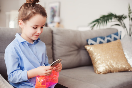 cute little child girl with mirror and cosmetic bag checking hairstyle at home. Pretend play and funny kids conceptの写真素材