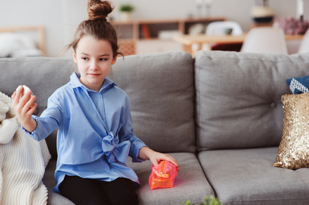cute little child girl with mirror and cosmetic bag checking hairstyle at home. Pretend play and funny kids conceptの写真素材