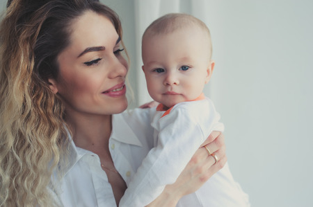 happy family at home. Mother holding baby son in bedroom in cozy weekend morningの写真素材