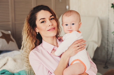 happy family at home. Mother holding baby son in bedroom in cozy weekend morningの写真素材