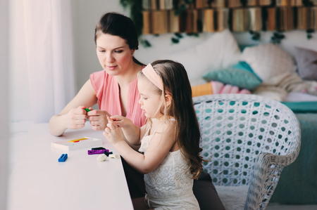 mother and toddler daughter playing with plasticine or play dough at home. Happy family learning in cozy weekend morningの写真素材