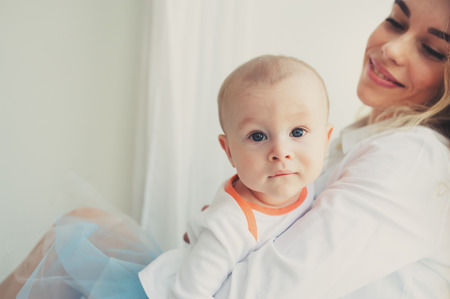 happy family at home. Mother holding baby son in bedroom in cozy weekend morningの写真素材