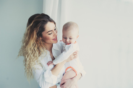 happy family at home. Mother holding baby son in bedroom in cozy weekend morningの写真素材