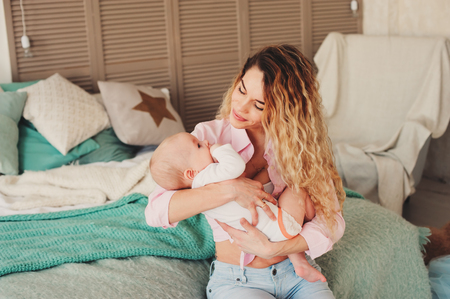 happy family at home. Mother holding baby son in bedroom in cozy weekend morningの写真素材
