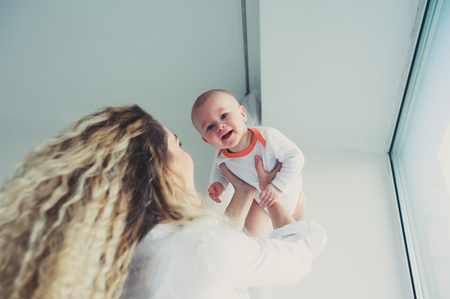 happy family at home. Mother holding baby son in bedroom in cozy weekend morningの写真素材
