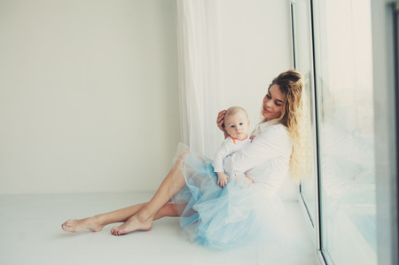 happy family at home. Mother holding baby son in bedroom in cozy weekend morningの写真素材