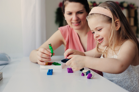mother and toddler daughter playing with plasticine or play dough at home. Happy family learning in cozy weekend morningの写真素材