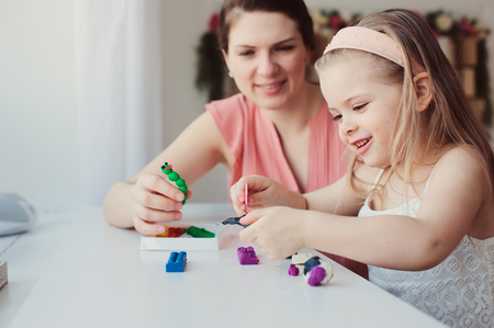 mother and toddler daughter playing with plasticine or play dough at home. Happy family learning in cozy weekend morningの写真素材