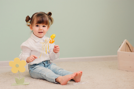 close up indoor portrait of cute happy baby girl playing with easter decorationsの写真素材