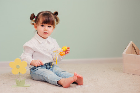 close up indoor portrait of cute happy baby girl playing with easter decorationsの写真素材