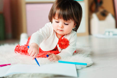 1 year old baby girl drawing with pencils at home. Early learning and education concept の写真素材