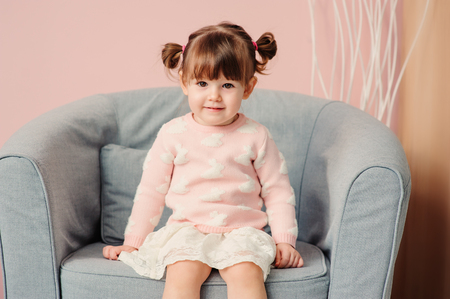 close up indoor portrait of cute happy 2 years old baby girl in pink sweaterの写真素材