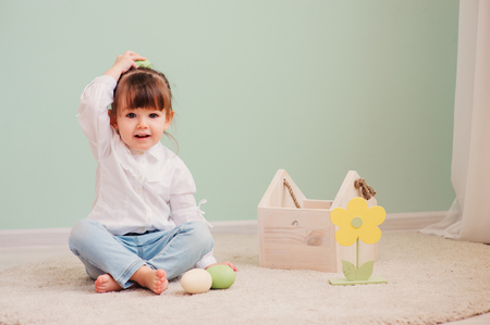 close up indoor portrait of cute happy baby girl playing with easter decorationsの写真素材