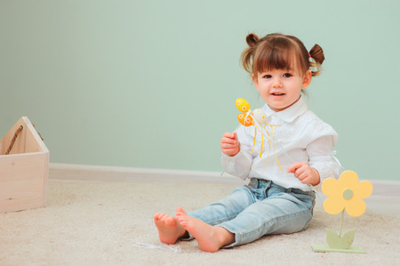 close up indoor portrait of cute happy baby girl playing with easter decorationsの写真素材