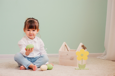 close up indoor portrait of cute happy baby girl playing with easter decorationsの写真素材