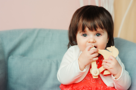 cute happy 1 year old baby girl playing with wooden toys at home. Modern nursery interior, early learning conceptの写真素材
