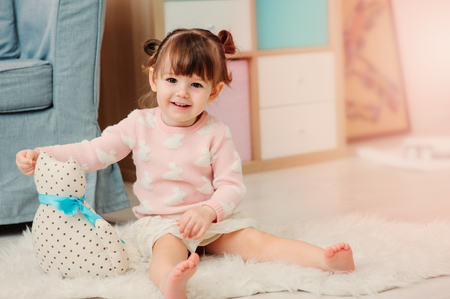cute happy 2 years old baby girl playing with toys at home. Modern nursery interior in pastele tones, early learning conceptの写真素材