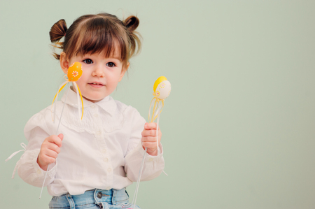 close up indoor portrait of cute happy baby girl playing with easter decorationsの写真素材
