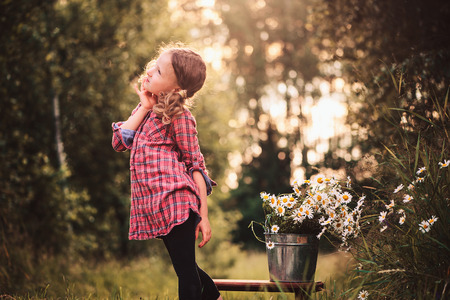 cute child girl picking flowers outdoor on summer field, cozy mood, rural sceneの写真素材
