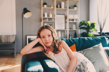 cute kid girl relaxing at home in cozy weekend morning in sunny living room with modern scandinavian interiorの写真素材