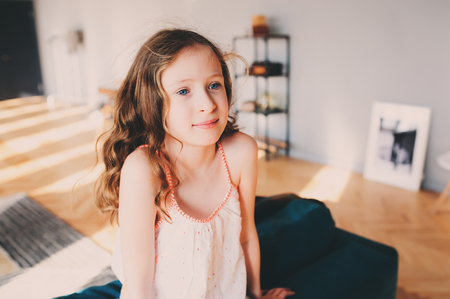 cute kid girl relaxing at home in cozy weekend morning in sunny living room with modern scandinavian interiorの写真素材