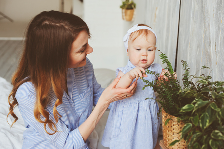 happy mother and 9 month old baby in matching pajamas playing in bedroom in the morning. Cozy family weekend.の写真素材