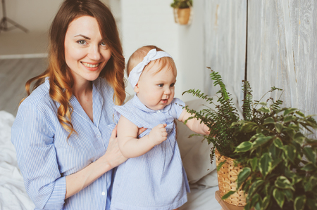 happy mother and 9 month old baby in matching pajamas playing in bedroom in the morning. Cozy family weekend.の写真素材