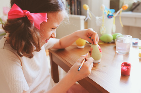 happy 7 years old kid girl painting easter eggs. Easter craft and holiday preparations at home.の写真素材