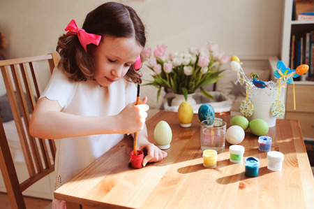 happy 7 years old kid girl painting easter eggs. Easter craft and holiday preparations at home.の写真素材