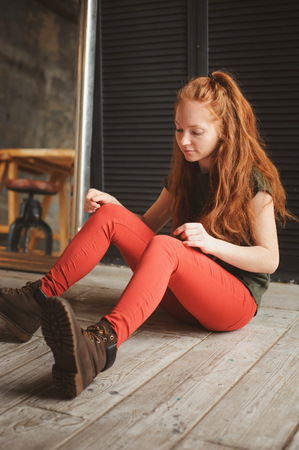 indoor portrait of beautiful young redhead woman dressed in hipster styleの写真素材