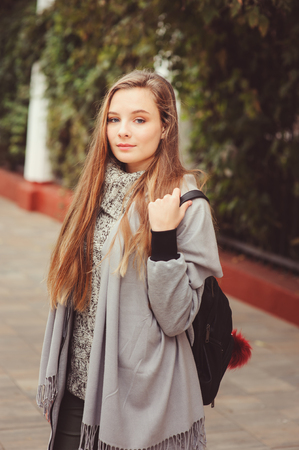 street style portrait of young beautiful happy girl walking in autumn city with trendy leather backpackの写真素材