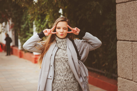 street style portrait of young beautiful happy girl walking in autumn city with trendy leather backpackの写真素材
