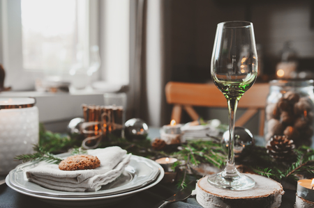 Festive Christmas and New Year table setting in scandinavian style with rustic handmade details in natural and white tones. Dining place decorated with pine cones, branches and candlesの写真素材