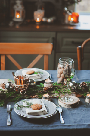 Festive Christmas and New Year table setting in scandinavian style with rustic handmade details in natural and white tones. Dining place decorated with pine cones, branches and candlesの写真素材