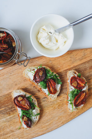 italian traditional bruschetta - bread toast with sun dried tomatoes, cream cheese, olive oil and arugula.の写真素材