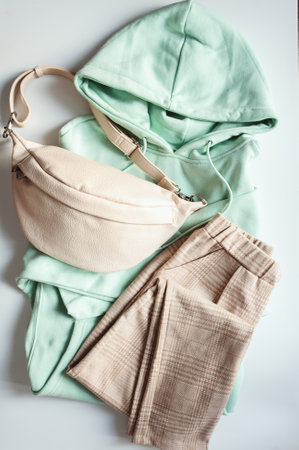 Casual comfortable outfit for women. Soft green hoodie, beige pants and leather bag.の写真素材