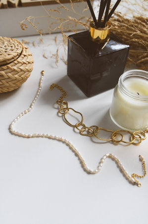 Minimalist home aesthetics. Fashion jewelery and candles setting on white background. Feminine trendy homeの写真素材