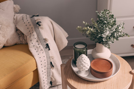 cozy spring home details. House plant, candle and decorations composition on coffee table with chair on background.の写真素材