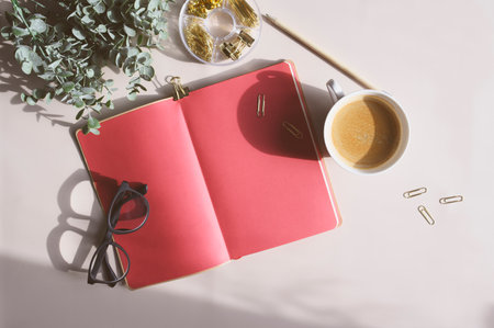 aesthetic minimalist workspace in trendy 2023 colors. Home office, blog and social media concept. Flat lay of note book, coffee and glasses in the morning sunの写真素材