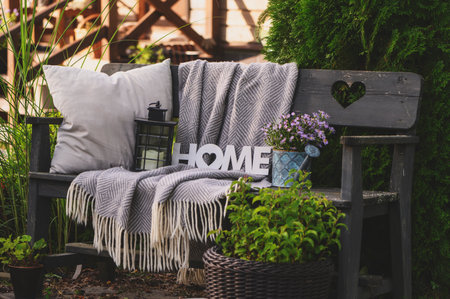 pillows and blanket on cozy rustic wooden bench in summer garden. Country living.の写真素材
