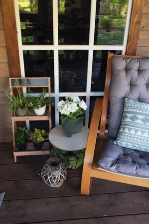 Summer patio and front porch decorations. Wooden chair, flower pots and lantern for cozy summertime relaxation.の写真素材