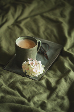 bedroom interior details with dark green bedlinen colors and cup of coffee