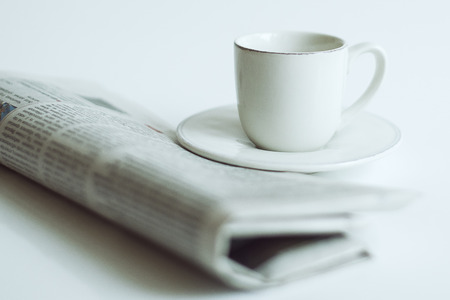 newspaper and a cup of coffee on a white backgroundの写真素材