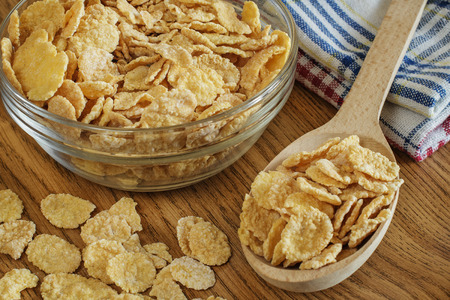 Corn flakes in a glass bowl on wooden background