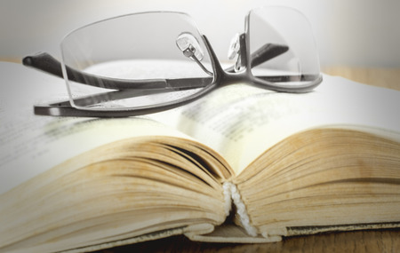 glasses stacked on a gross book on the tableの写真素材