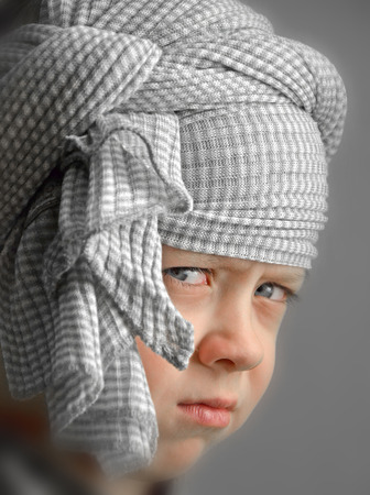boy with a turban on his head with a serious lookの写真素材