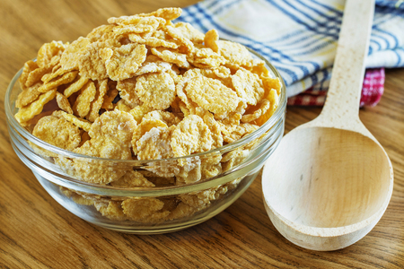 Corn flakes in a glass bowl on wooden backgroundの写真素材