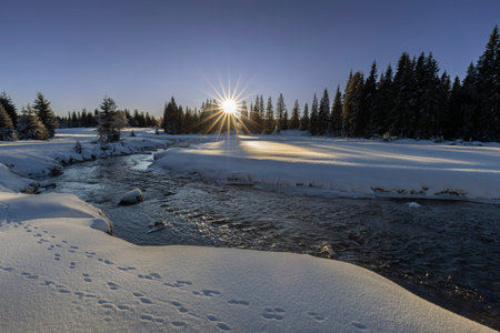 Beautiful winter landscape with a frozen river in the forest at sunset. Landcapa of Å umava....
